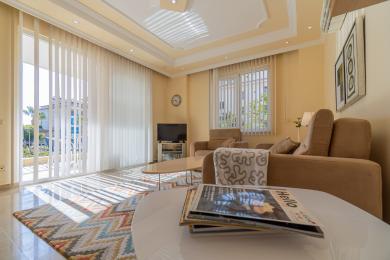 Alanya Immobilie Wohnzimmer mit beigen Sofas, hellem Licht, Jalousien und einer entspannten, komfortablen Atmosphäre.