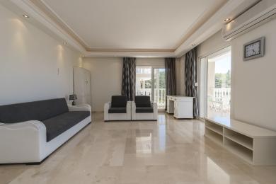 Lichte Alanya woonkamer met marmeren vloeren, bank, fauteuils en toegang tot het balkon, waardoor een ruimtelijk en luchtig gevoel ontstaat.