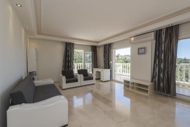 Lichte Alanya woonkamer met marmeren vloeren, grijze bank, toegang tot het balkon en een neutrale inrichting zorgt voor een serene sfeer.