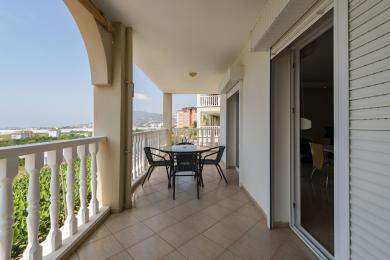 Alanya'da karo zeminli, beyaz korkuluklu ve şehre bakan yemek masası olan balkon.