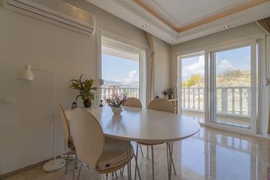 Mermer zeminli, beyaz masalı ve manzaralı balkon erişimi sunan aydınlık Alanya yemek odası.
