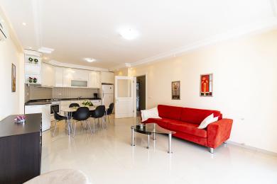 Bright apartment showcasing an open-plan kitchen and living area, featuring modern decor and sleek, tiled floors.