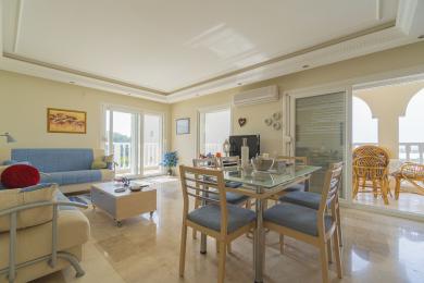 Mermer zeminli, cam yemek masalı ve balkon erişimli, rahat bir atmosfer yaratan aydınlık Alanya oturma odası.