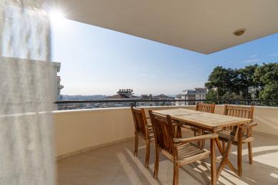 Alanya woning balkon met houten tafel/stoelen, tegelvloer en helder, zonnig uitzicht op de stad.