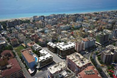 Alanya ingatlan légifelvétele, amely modern apartmanházakat mutat a strand és a város közelében.