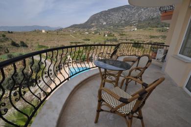 Varanda de propriedade em Alanya com móveis de vime, grade de ferro forjado e vistas panorâmicas da montanha.