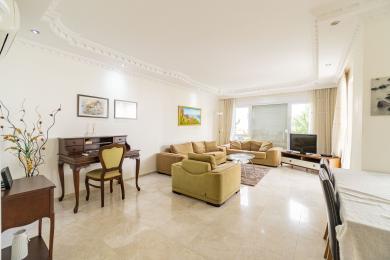 Luminoso soggiorno ad Alanya con pavimenti in marmo, divani confortevoli e una classica scrivania sotto modanature decorative del soffitto.