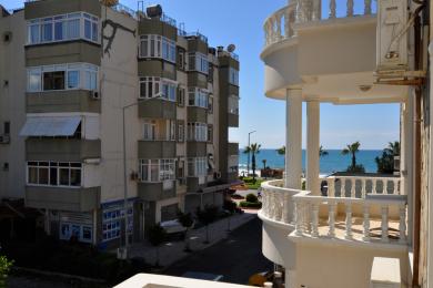 Varanda de propriedade em Alanya com grades e colunas brancas ornamentadas, oferecendo uma vista luminosa e ensolarada do mar.