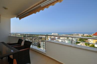 Alanya woning balkon met wicker meubilair en prachtig panoramisch uitzicht op zee en de stad.