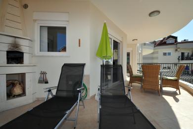 Alanya woning balkon met ligstoelen, openhaard en wicker meubilair, biedt een ontspannen, zonovergoten sfeer.