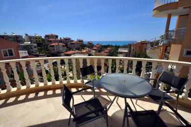 Alanya-Immobilienbalkon mit Marmorboden, weißen Geländern und Sitzgelegenheiten im Freien mit Blick auf das Mittelmeer.