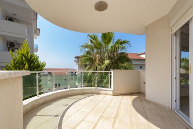 Balcon de propriété à Alanya avec revêtement de sol en carrelage, balustrades en verre et ambiance extérieure lumineuse et ensoleillée.