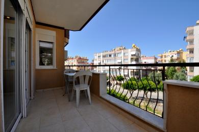Alanya ejendom altan med flisegulv, smedejerns gelænder og lys, solrig atmosfære.