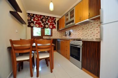 Alanya fastighet kök med träskåp, mosaik kakel, matbord och ljus, inbjudande atmosfär.