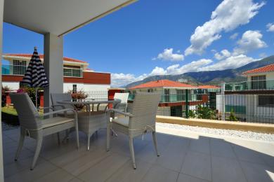 Balkon nekretnine u Alanji sa namještajem od pruća, podom od pločica i svijetlim, sunčanim pogledom na planine.