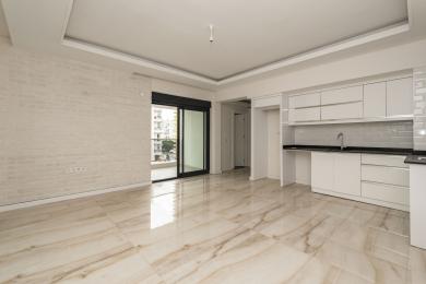Propriedade em Alanya: Sala de estar moderna e luminosa com pisos de mármore, parede de tijolos brancos e área de cozinha elegante.