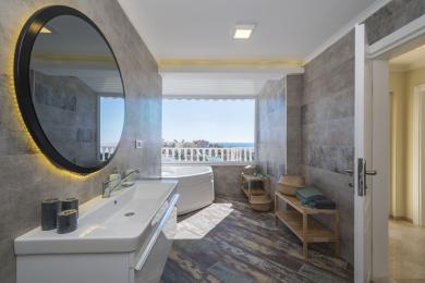 Koupelna v nemovitosti Alanya s vířivkou, moderním umyvadlem, dlaždicemi se vzhledem dřeva a jasným výhledem na oceán.