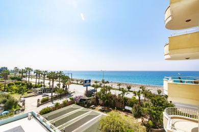 Alanya fastighets balkongvy som visar det turkosa havet och palmkantade stranden under en ljus, solig himmel.