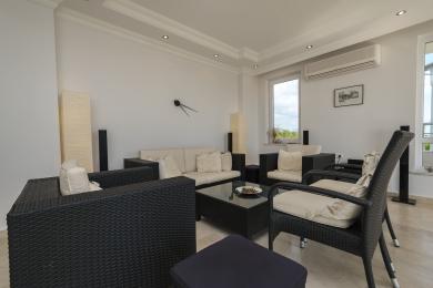 Sala de estar luminosa em Alanya com móveis de vime, almofadas neutras e luz natural, criando uma atmosfera relaxante.