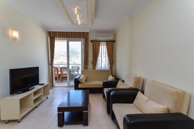 Soggiorno di una proprietà ad Alanya con accesso al balcone, divani confortevoli, tonalità neutre e illuminazione naturale e luminosa.