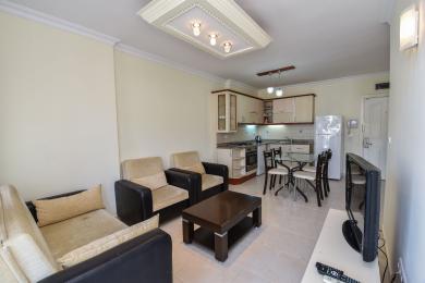 Proprietà di Alanya: soggiorno e cucina open space con pavimenti in piastrelle, mobili moderni e comoda area salotto.