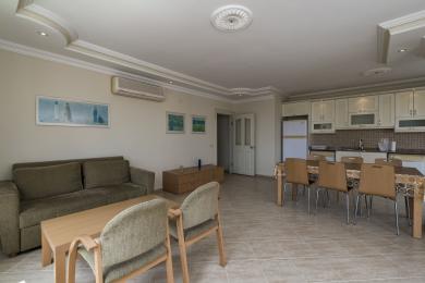 Alanya onroerend goed woonkamer beschikt over een bank, eethoek en keuken met lichte houten kasten en tegelvloeren.