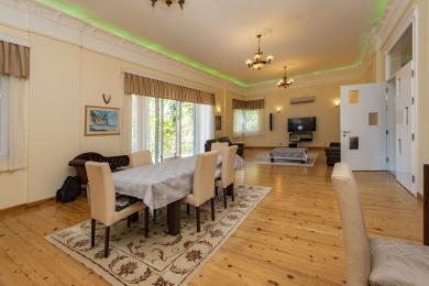 A área de jantar e estar da propriedade de Alanya apresenta pisos de madeira, lustres elegantes e luz natural e brilhante.