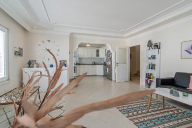 Jasny salon w Alanyi z otwartą kuchnią, białymi szafkami, kafelkami na podłodze i nowoczesną, komfortową atmosferą.