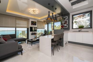 Den moderne stuen i Alanya-leiligheten har en elegant kjøkkenøy, havutsikt og stilfull pendelbelysning.