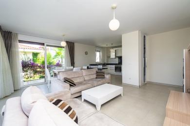 Lichte Alanya woonkamer met tegelvloeren, zachte banken en uitzicht op weelderig groen.