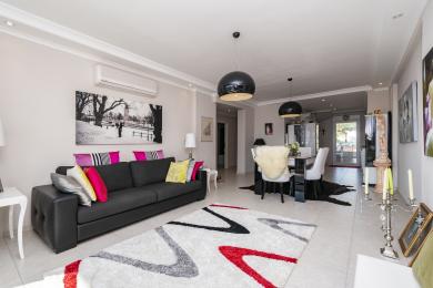 De heldere woonkamer in Alanya beschikt over een moderne sofa, een eethoek en een stijlvolle inrichting met neutrale tinten.