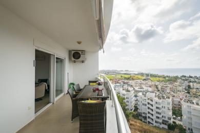 Alanya woning balkon met wicker meubilair, tegelvloer en prachtig uitzicht op de stad en de zee.