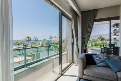 Luminosa sala de estar en Alanya con un sofá, ventanas de piso a techo e impresionantes vistas al mar desde el balcón.