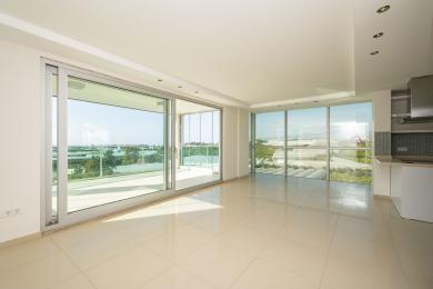 Světlý obývací pokoj v apartmánu v Alanyi s dlaždicovou podlahou, okny od podlahy ke stropu a přístupem na balkon s malebným výhledem.