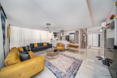 Světlý, otevřený obývací pokoj v Alanyi nabízí moderní kuchyň, plyšové pohovky, mramorové podlahy a elegantní závěsná svítidla.