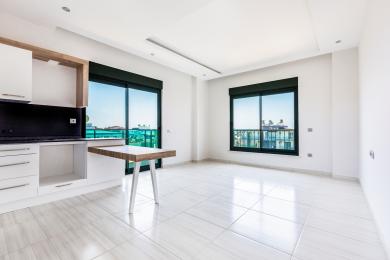 Aydınlık, modern Alanya mutfağı beyaz dolaplara, bir kahvaltı barına ve şehir manzaralı büyük pencerelere sahiptir.