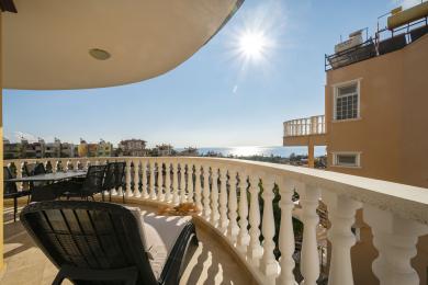 Balkon nekretnine u Alanji sa namještajem od pruća, mramornom ogradom i jarkim suncem s pogledom na Sredozemno more.