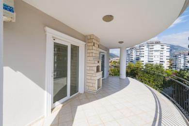 Balcon lumineux et incurvé à Alanya avec carrelage, élément en brique et vue panoramique sur la montagne.