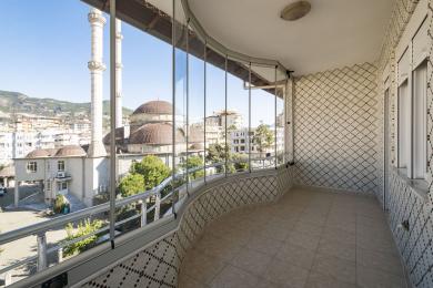 Şəffaf bağlı, kafel döşəməli və divarlı, parlaq şəhər və məscid mənzərələri təqdim edən Alanya mülkündəki balkon.
