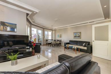 Luminoso soggiorno ad Alanya con pavimenti in marmo, divani in pelle, zona pranzo e accesso al balcone con vista sulla città.