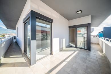 Het heldere balkon in Alanya is voorzien van tegelvloeren, witte muren, donkeromlijste schuifdeuren en uitzicht op de bergen, waardoor een moderne, luchtige ruimte ontstaat.