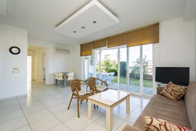 Lichte Alanya woonkamer met tegelvloeren, rotan stoelen en schuifdeuren naar een privétuin.