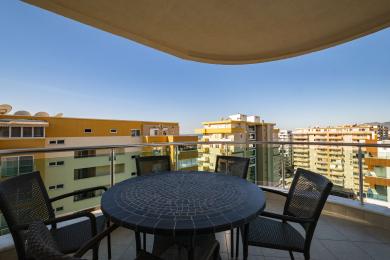 Alanya woning balkon met een mozaïek tafel, rieten stoelen, glazen balustrades en helder uitzicht op de stad.