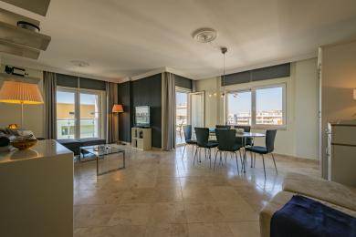 Een heldere woonkamer in Alanya met marmeren vloeren, een donkere accentmuur, toegang tot het balkon en een moderne eethoek.