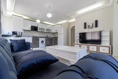 Dnevna soba apartmana u Alanji s modernom kuhinjom, plišanim plavim kaučem i svijetlom, ugodnom atmosferom.