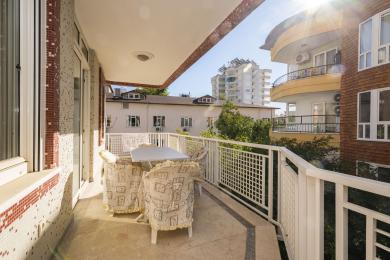 Zonnig Alanya balkon met mozaïekmuren, stenen vloer en buitenset, waardoor een ontspannen sfeer ontstaat.
