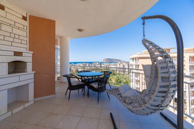 Rymlig balkong i Alanya med utomhusmatplats, hängstol och havsutsikt.