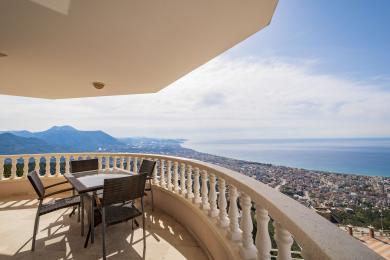 Svalir á fasteign í Alanya með húsgögnum úr víð og stórkostlegu víðáttumiklu útsýni yfir sjó og fjöll.