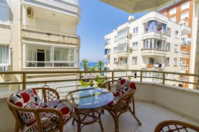 Balkon nekretnine u Alanji sa nameštajem od ratana, staklenim stolom i svetlim, sunčanim pogledom na more.