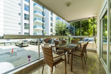Alanya woning: Lichte, afgesloten balkon met glazen wanden, wicker meubels en een ontspannen, luchtige sfeer.